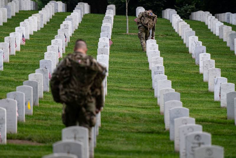 ARLINGTON, VIRGINIA - MAY 23: Members of the 3rd U.S. Infantry Regiment, also known as the "Old Guard," place flags at the headstones of U.S. military personnel buried at Arlington National Cemetery ahead of Memorial Day, on May 23, 2024 in Arlington, Virginia. Nearly 1,500 joint service members will spend around four hours placing small American flags in front of more than 260,000 headstones. The cemetery, consisting of 639 acres, is the final resting place of approximately 400,000 veterans and their dependents. (Photo by Kent Nishimura/Getty Images)