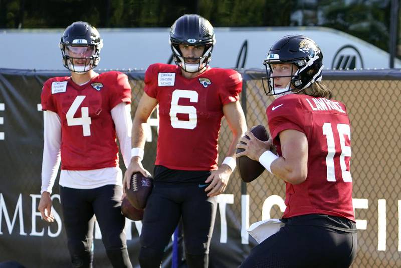 Jacksonville Jaguars quarterback Trevor Lawrence (16) runs through a drill as quarterback's Kyle Sloter (4) and Jake Luton (6) look on during an NFL football practice, Sunday, July 31, 2022, in Jacksonville, Fla.