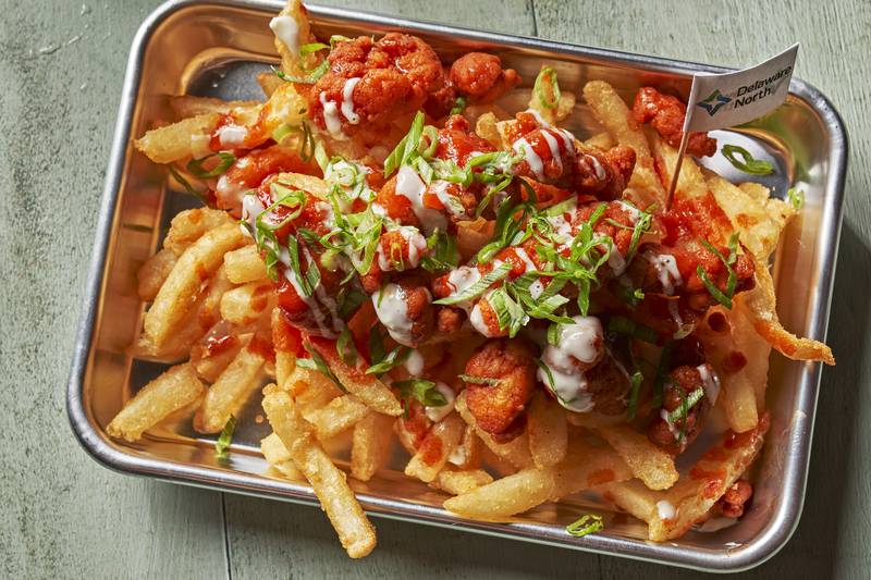 Buffalo Chicken Fries: Popcorn chicken tossed in buffalo sauce, topped with blue cheese sauce and scallions. Served on a bed of fries.