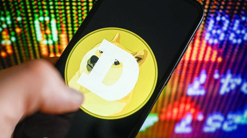 POLAND - 2024/04/25: In this photo illustration the Dogecoin logo is displayed on a smartphone with stock market percentages in the background. (Photo Illustration by Omar Marques/SOPA Images/LightRocket via Getty Images)
