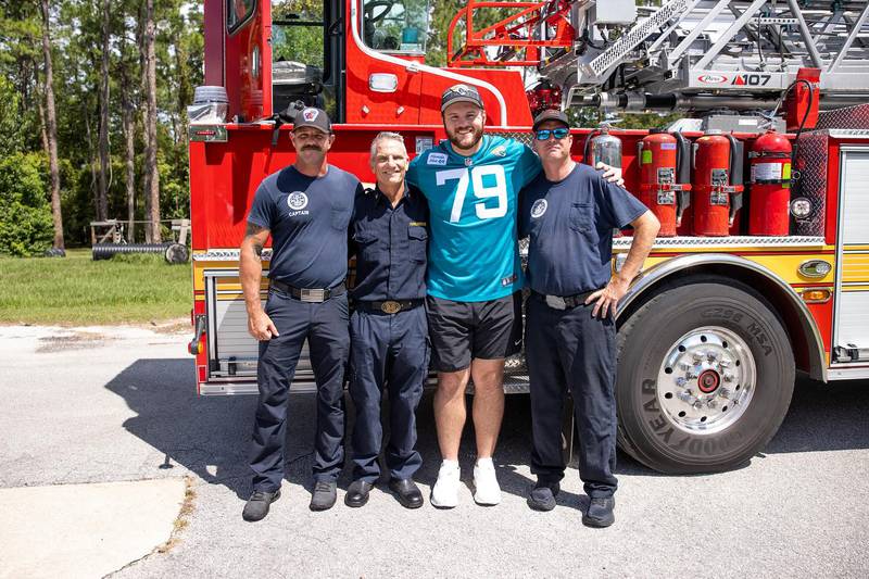 Luke Fortner posing with members of the Jacksonville Fire Rescue Department.