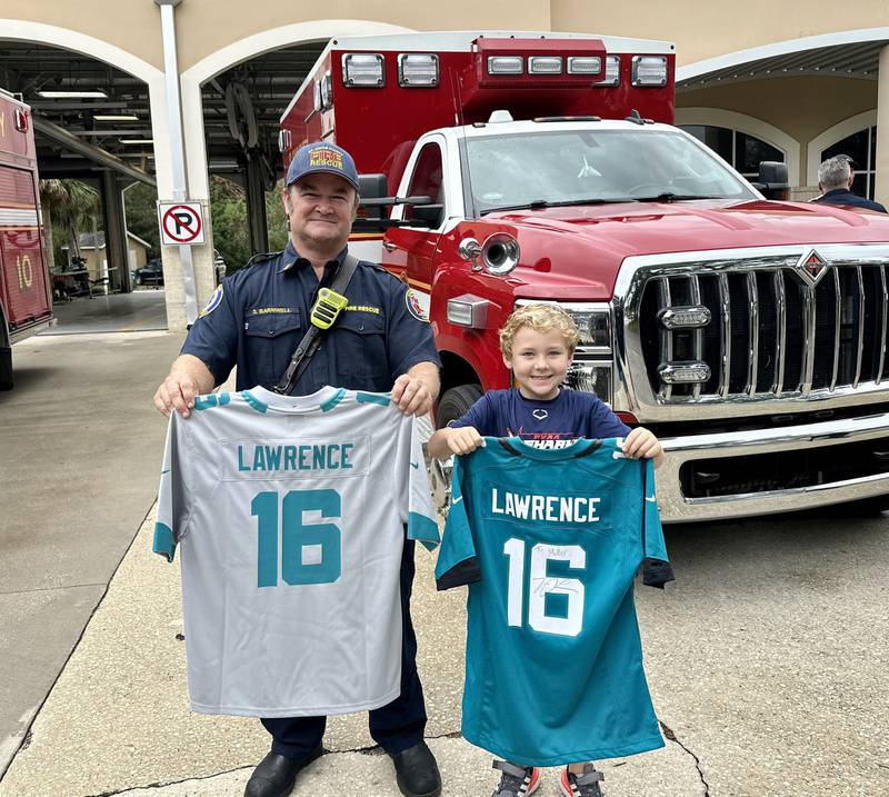 Miller poses with SJCFR Captain Scott Barnwell with the replacement jersey and the one signed by Trevor Lawrence.