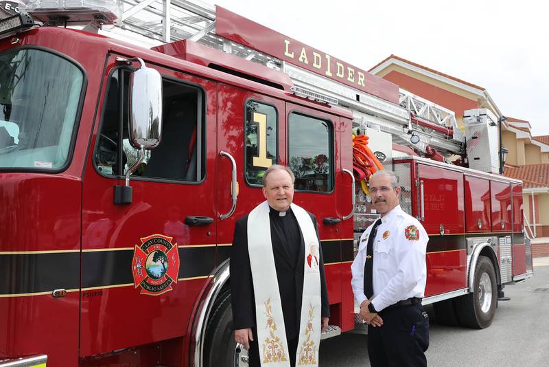 Acting Fire Chief David Motes and Fr. Andy Blaszkowski pose infront of the new Fire Engine/Ladder 1.