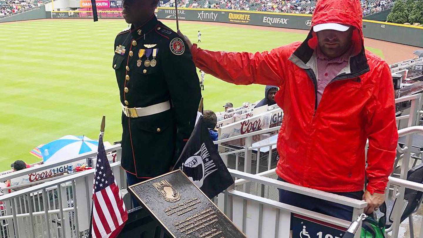 Baseball fan stands in rain to hold umbrella over JROTC member