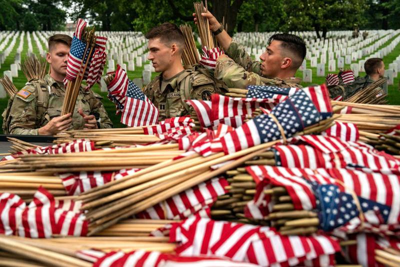 ARLINGTON, VIRGINIA - MAY 23: Members of the 3rd U.S. Infantry Regiment, also known as the "Old Guard," get ready to place flags at the headstones of U.S. military personnel buried at Arlington National Cemetery ahead of Memorial Day, on May 23, 2024 in Arlington, Virginia. Nearly 1,500 joint service members will spend around four hours placing small American flags in front of more than 260,000 headstones. The cemetery, consisting of 639 acres, is the final resting place of approximately 400,000 veterans and their dependents. (Photo by Kent Nishimura/Getty Images)
