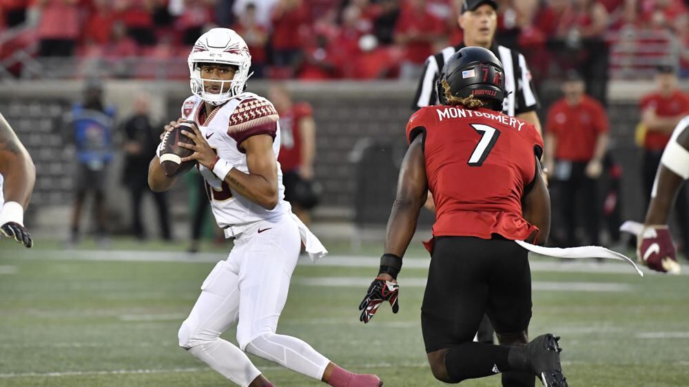 Florida State quarterback Jordan Travis (13) is pursued by Louisville linebacker Monty Montgomery (7) during the first half of an NCAA college football game in Louisville, Ky., Friday, Sept. 16, 2022.