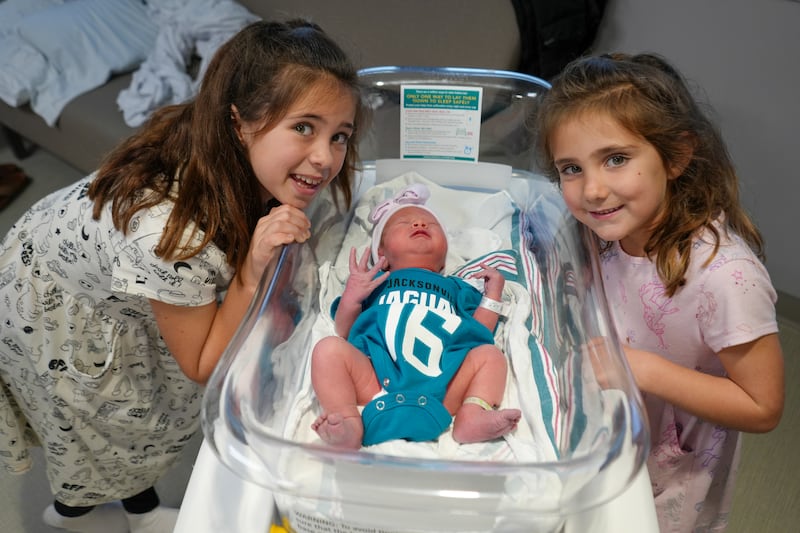 Babies from various local Baptist Health hospitals wearing Trevor Lawrence jersey onesies