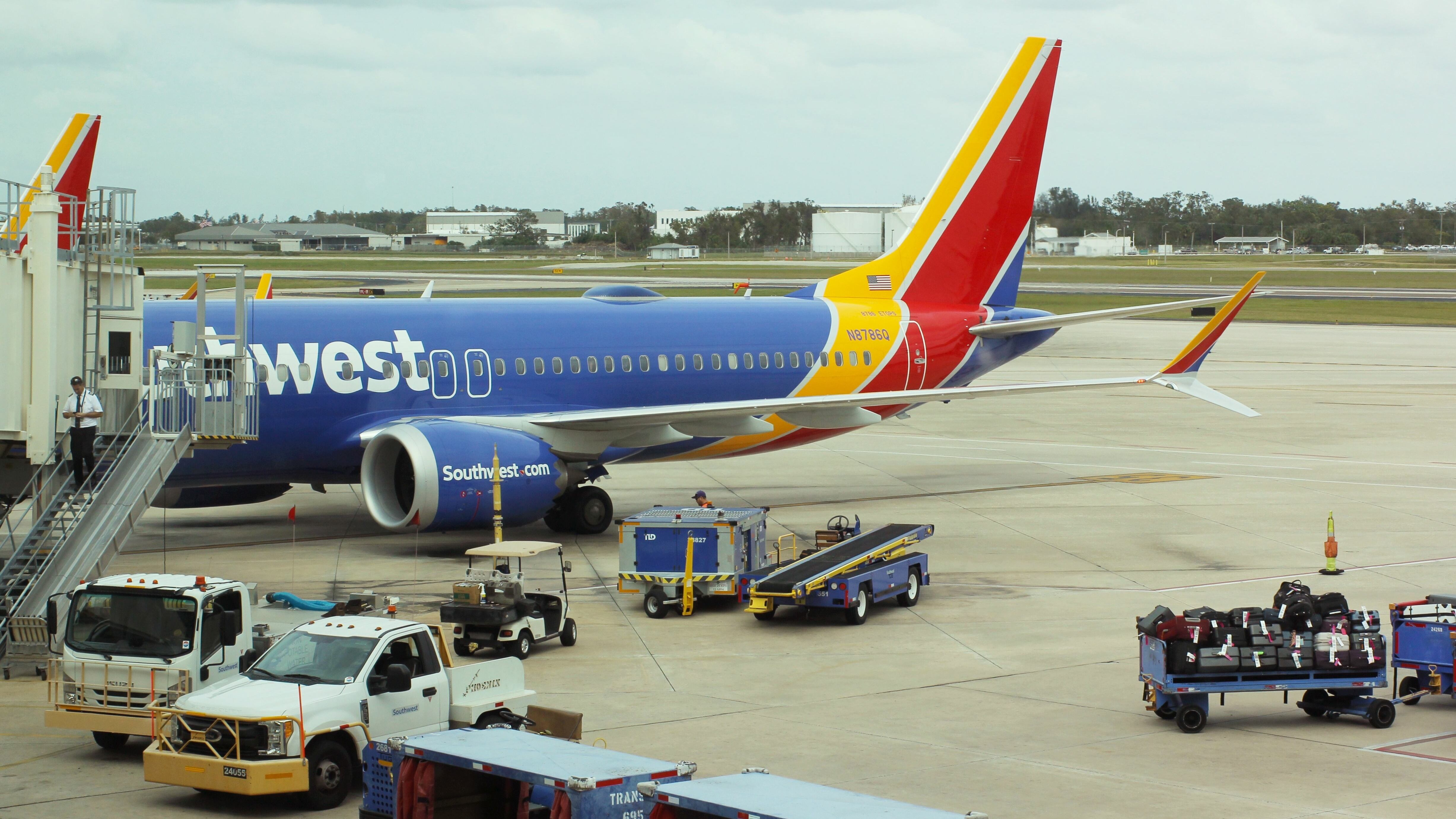 Southwest plane with baggage staged outside on trailers.
