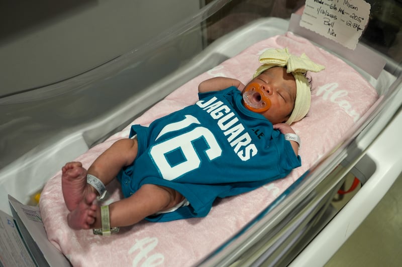 Babies from various local Baptist Health hospitals wearing Trevor Lawrence jersey onesies