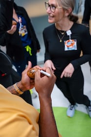 Jags RB Travis Etienne signs mini footballs for the children at Nemours Children's Health.