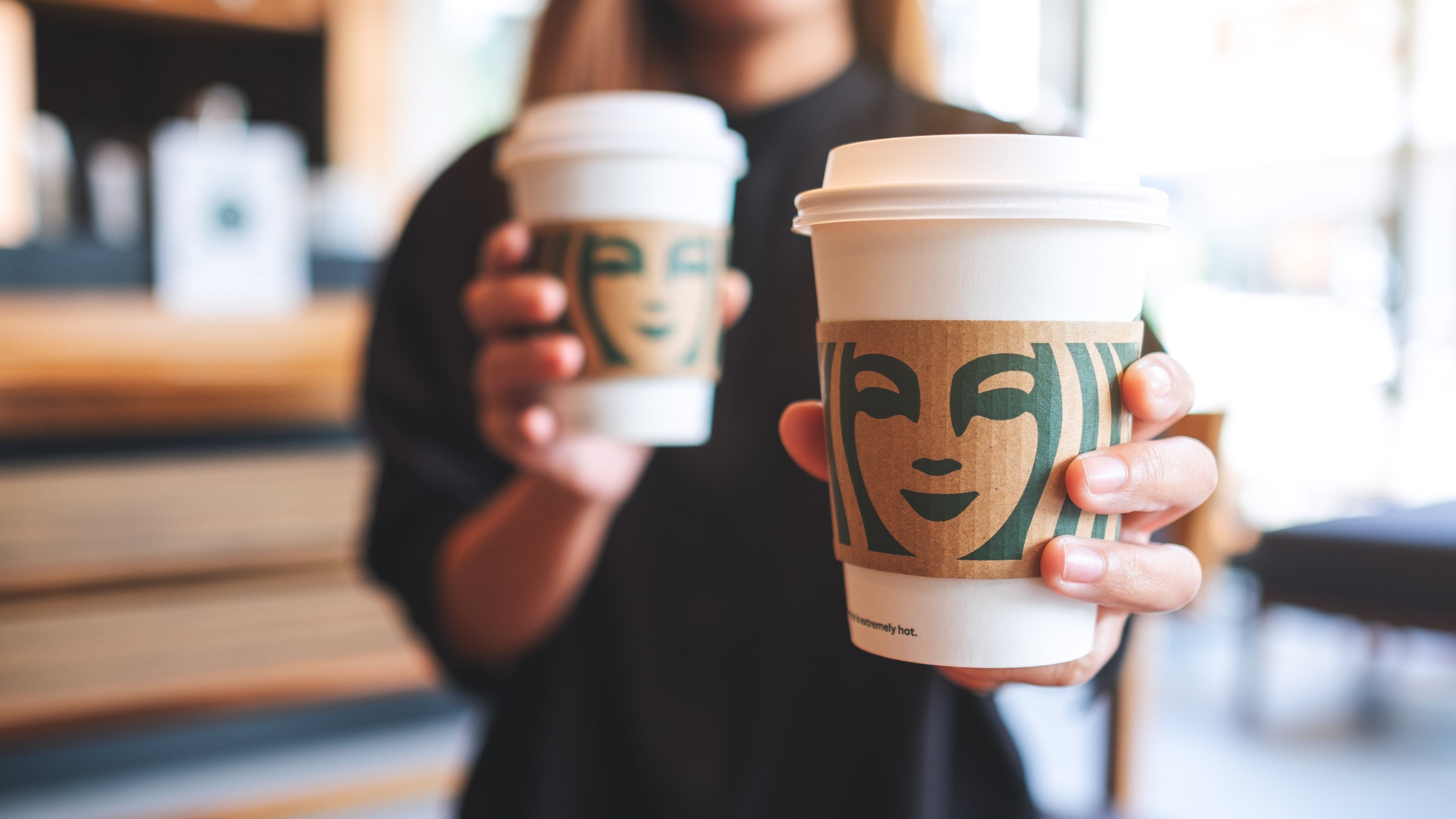 Closeup of a woman holding and serving two cup of hot coffee.