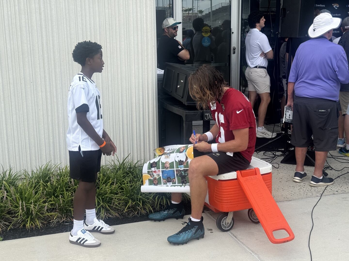 Jaguars QB Trevor Lawrence signs an autograph for a young fan, 7/29/26