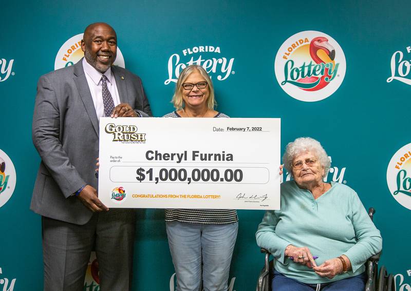 Cheryl Furnia poses with Florida Lottery Chief of Staff Reggie Dixon, her mother, and an oversized check after claiming a $1 million top prize from the GOLD RUSH SUPREME Scratch-Off game at Florida Lottery Headquarters in Tallahassee.